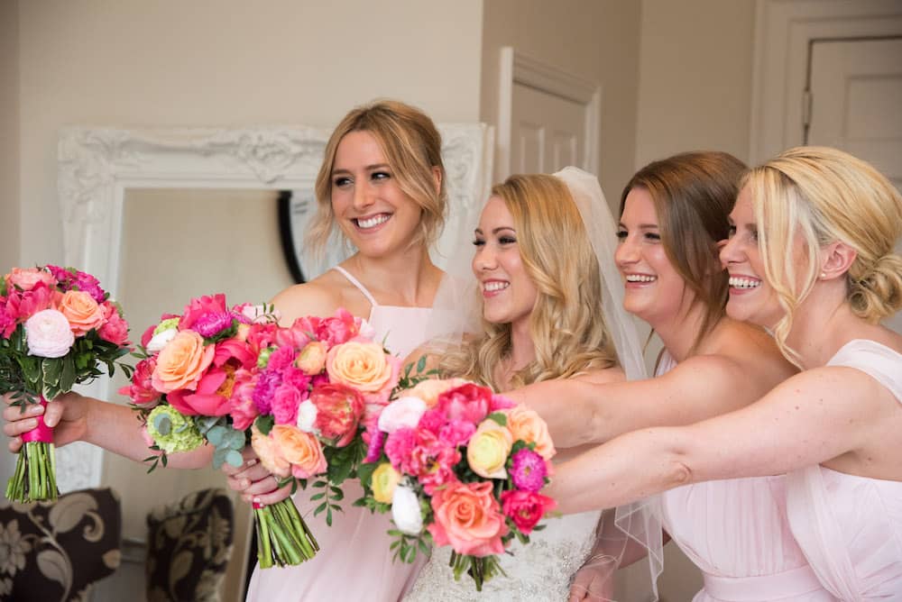 bridesmaids with bright pink and peach flowers with blush pink dresses