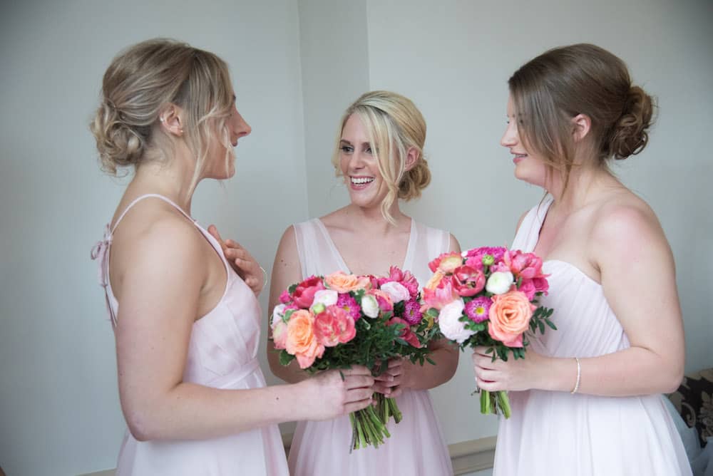 bridesmaids in pale pink dresses with bright flowers