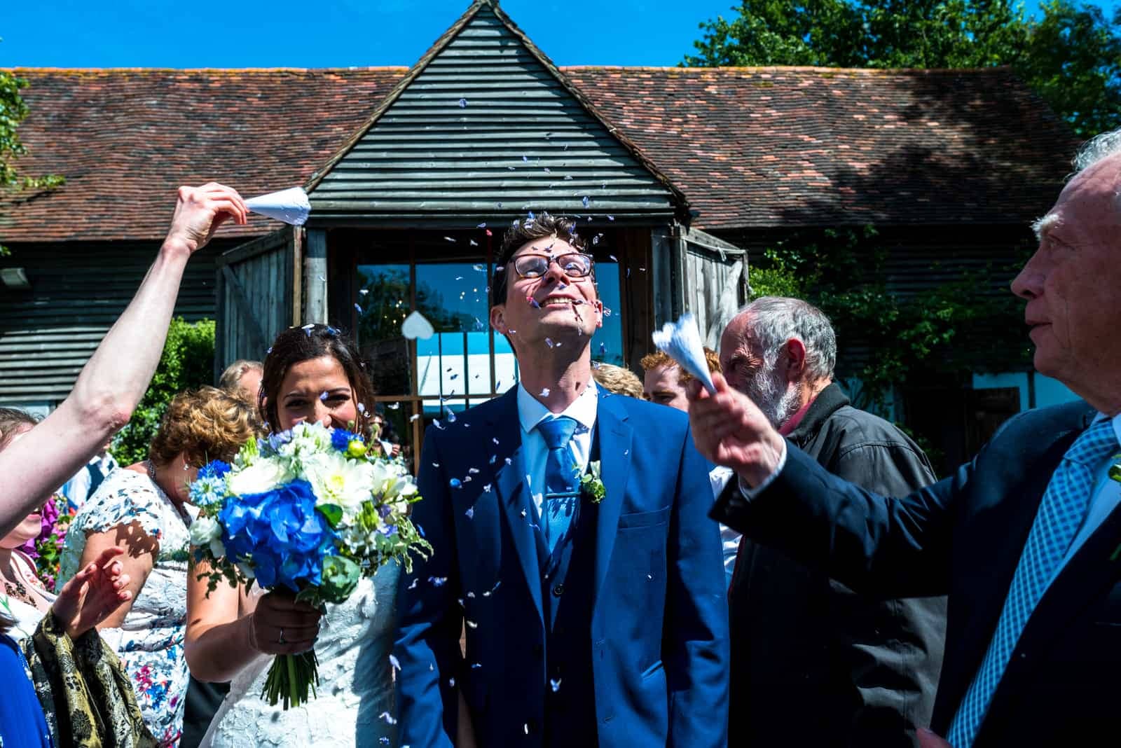 Bride and groom with flowers and confetti at East Sussex Wedding Venue