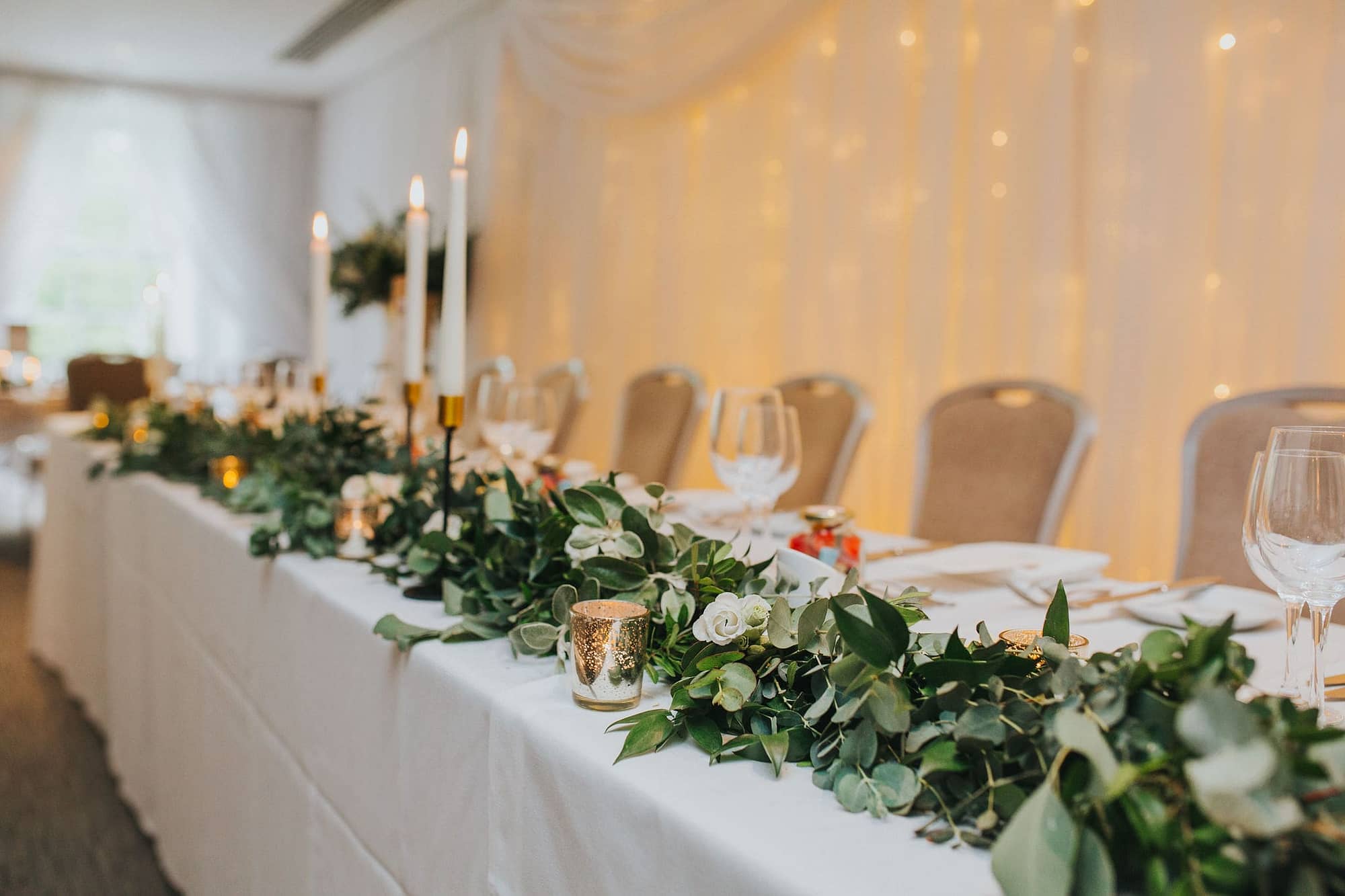 Top table foliage runner with eucalyptus and white roses at Alexander House